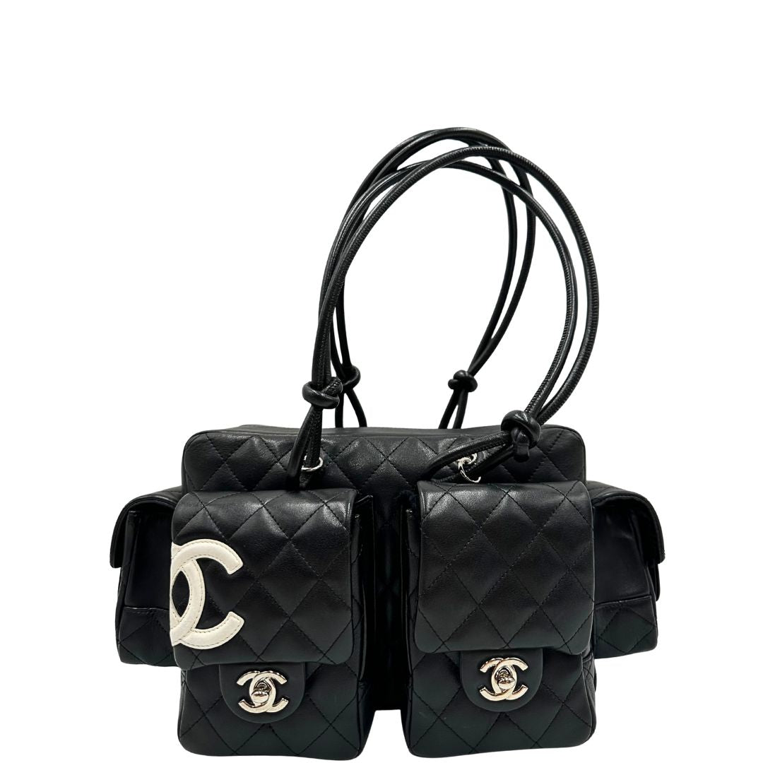 Front di una borsa Cambon Reporter Chanel in pelle trapuntata nera e doppie C bianche sul front, con tasche per accessori e doppi manici medio lunghi, rifinita con parti metalliche argentate. Completa di dustbag e card d'autenticità. Indossabile a spalla.