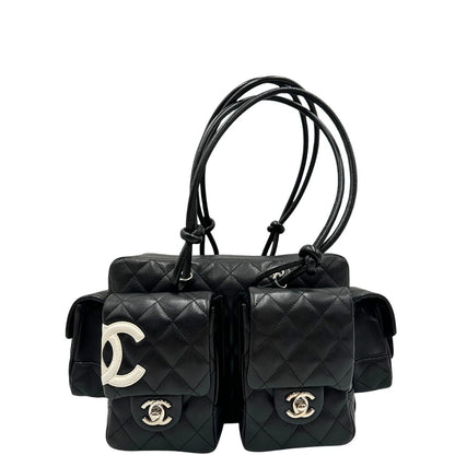 Front di una borsa Cambon Reporter Chanel in pelle trapuntata nera e doppie C bianche sul front, con tasche per accessori e doppi manici medio lunghi, rifinita con parti metalliche argentate. Completa di dustbag e card d'autenticità. Indossabile a spalla.