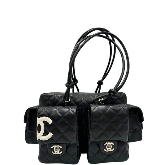 Front di una borsa Cambon Reporter Chanel in pelle trapuntata nera e doppie C bianche sul front, con tasche per accessori e doppi manici medio lunghi, rifinita con parti metalliche argentate. Completa di dustbag e card d'autenticità. Indossabile a spalla.