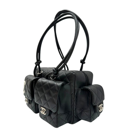 Laterale destro di una borsa Cambon Reporter Chanel in pelle trapuntata nera e doppie C bianche sul front, con tasche per accessori e doppi manici medio lunghi, rifinita con parti metalliche argentate. Completa di dustbag e card d'autenticità. Indossabile a spalla.