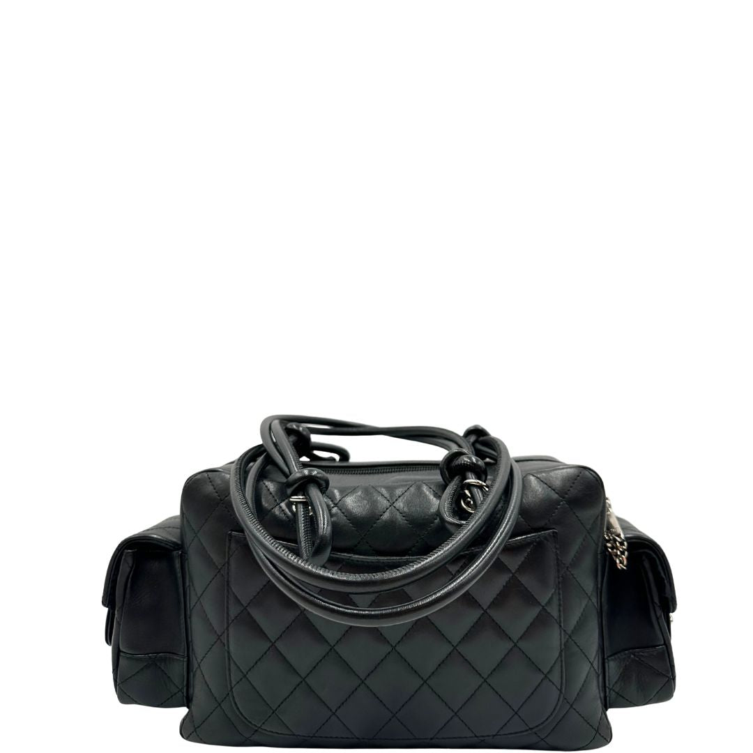 Retro di una borsa Cambon Reporter Chanel in pelle trapuntata nera e doppie C bianche sul front, con tasche per accessori e doppi manici medio lunghi, rifinita con parti metalliche argentate. Completa di dustbag e card d'autenticità. Indossabile a spalla.