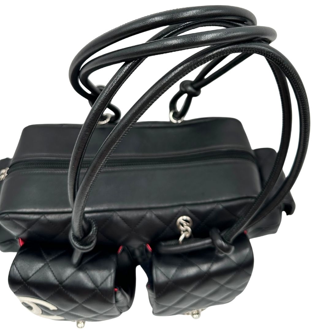 Manici di una borsa Cambon Reporter Chanel in pelle trapuntata nera e doppie C bianche sul front, con tasche per accessori e doppi manici medio lunghi, rifinita con parti metalliche argentate. Completa di dustbag e card d'autenticità. Indossabile a spalla.