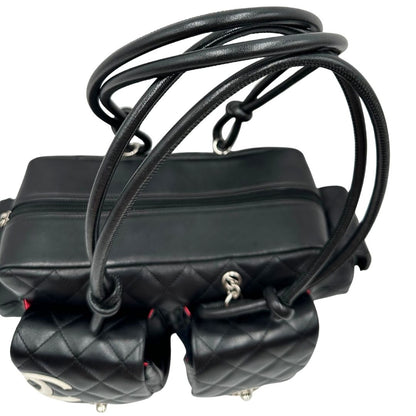 Manici di una borsa Cambon Reporter Chanel in pelle trapuntata nera e doppie C bianche sul front, con tasche per accessori e doppi manici medio lunghi, rifinita con parti metalliche argentate. Completa di dustbag e card d'autenticità. Indossabile a spalla.