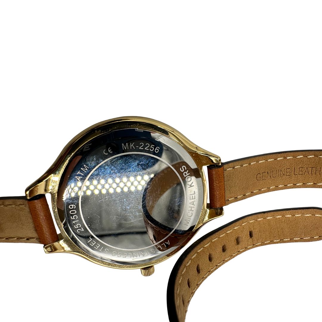 Orologio Michael Kors con cassa dorata e quadrante oro, dotato di cinturino in pelle color caramello a doppio giro, movimento al quarzo, cassa in acciaio inox con impermeabilità 5 ATM, quadrante analogico con indici a barre e lancette ore-minuti-secondi, chiusura ad ardiglione inciso Michael Kors, fondello in acciaio con riferimenti al modello MK-2256 e codice seriale, fornito con scatola ed etichetta.