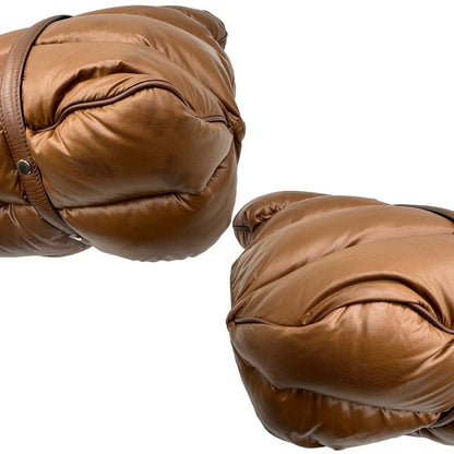 Angoli di una borsa Moncler in poliuretano color caramello effetto imbottito e finiture in pelle tono su tono, con metalleria dorata. Munita di cartellino. Da indossare a spalla.