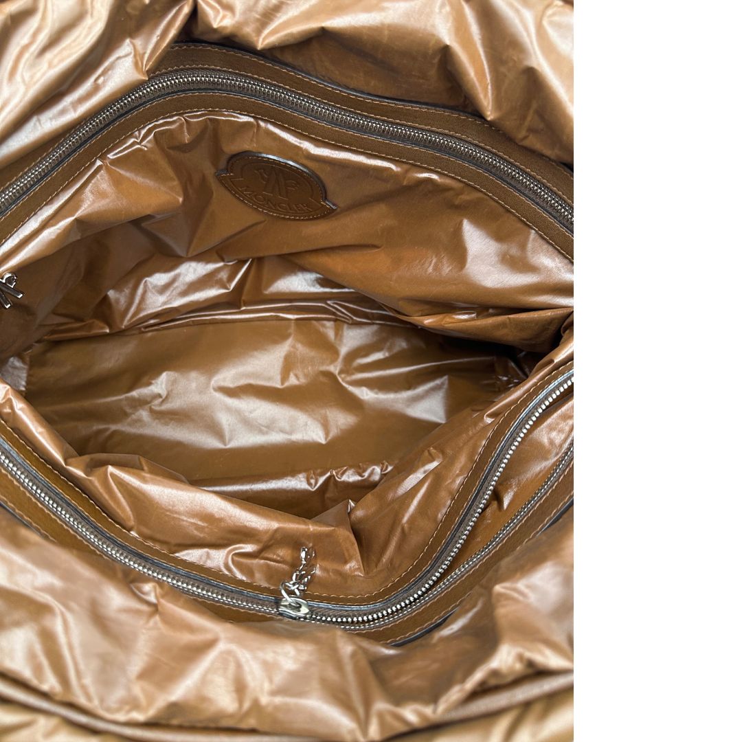 Interno di una borsa Moncler in poliuretano color caramello effetto imbottito e finiture in pelle tono su tono, con metalleria dorata. Munita di cartellino. Da indossare a spalla.