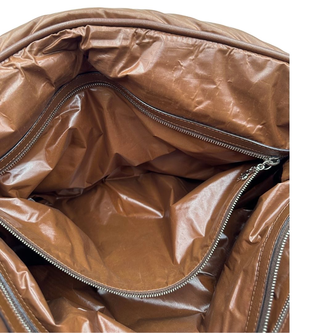 Interno di una borsa Moncler in poliuretano color caramello effetto imbottito e finiture in pelle tono su tono, con metalleria dorata. Munita di cartellino. Da indossare a spalla.