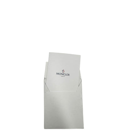 Cartellino di una borsa Moncler in poliuretano color caramello effetto imbottito e finiture in pelle tono su tono, con metalleria dorata. Da indossare a spalla.