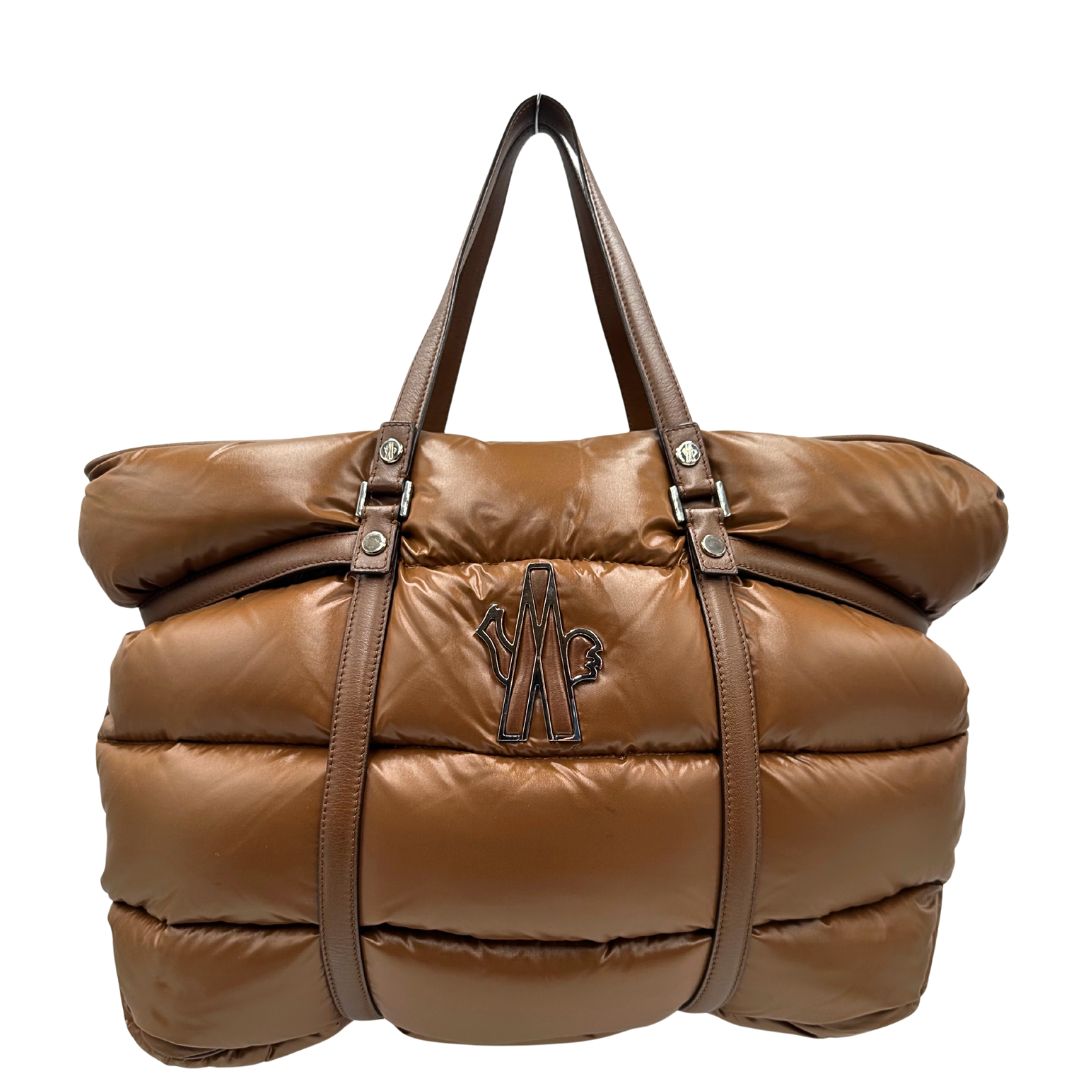 Front di una borsa Moncler in poliuretano color caramello effetto imbottito e finiture in pelle tono su tono, con metalleria dorata. Munita di cartellino. Da indossare a spalla.