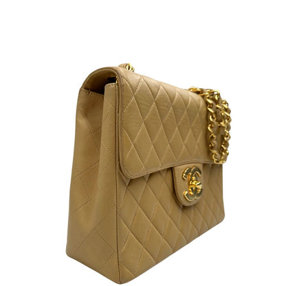 Laterale sinistro di una borsa Chanel in pelle beige matelassè e parti metalliche dorate; munita di una tracolla scorrevole in catena e pelle. Indossabile a spalla e a tracolla. Completa di scatola, dustbag e card d'autenticità.
