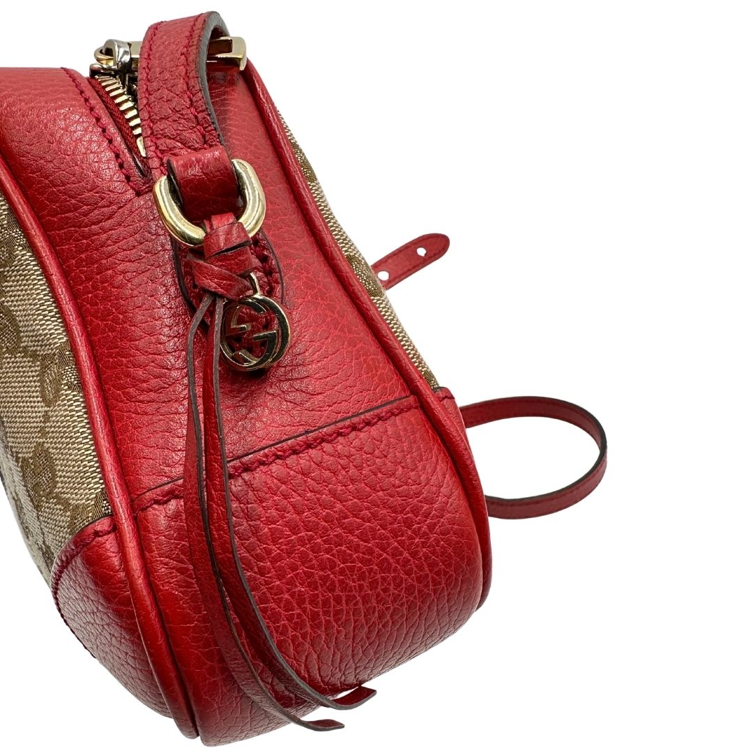 Borsa Gucci in tessuto GG beige con finiture in pelle martellata rossa e parti metalliche dorate; munita di una tracoll regolabile. Completa di dustbag. Originale, usata, di lusso, in ottime condizioni.