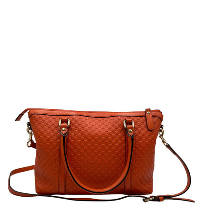 Retro di una borsa Gucci in pelle arancione GG con parti metalliche dorate; munita di doppi manici e una tracolla amovibile e regolabile.