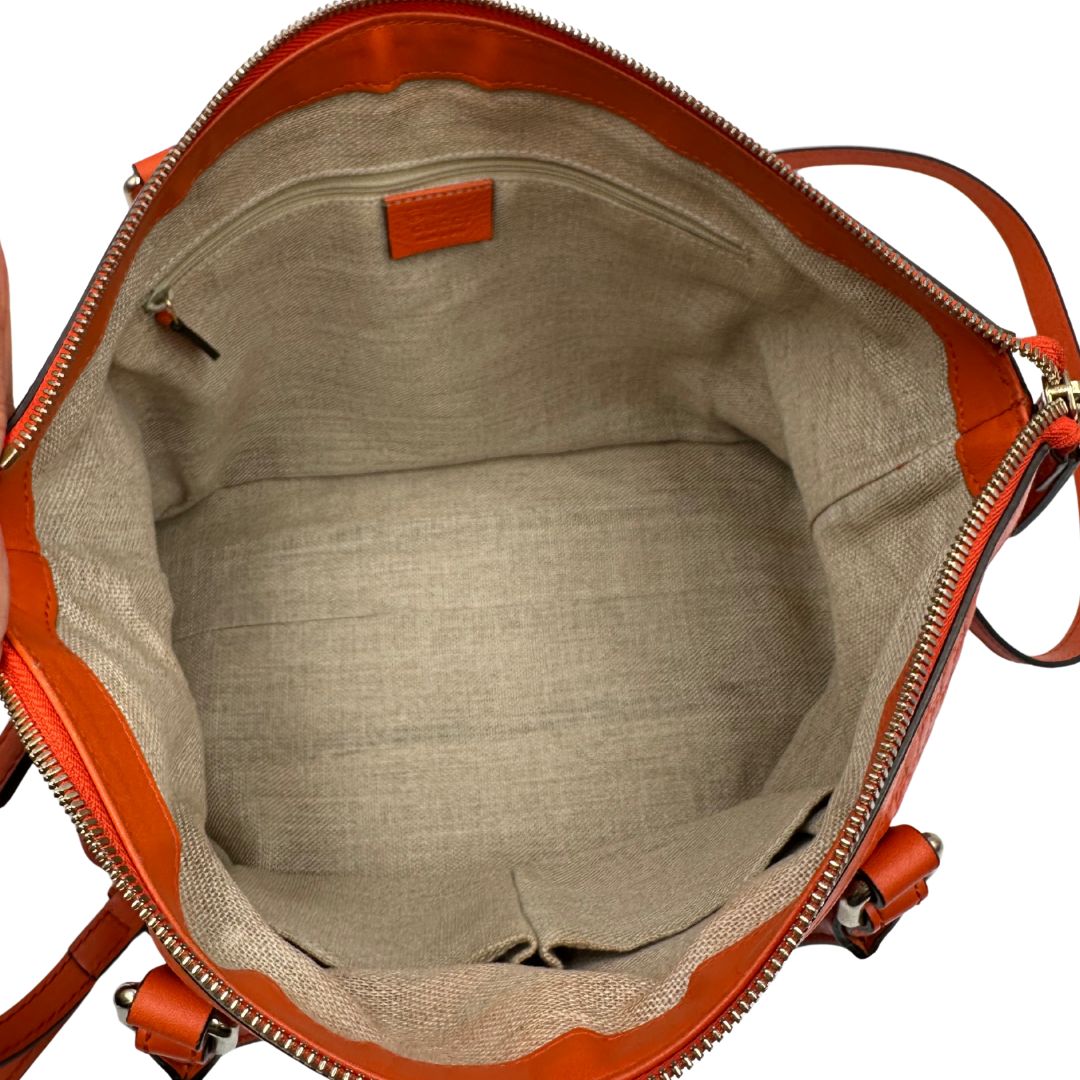 Interno di una borsa Gucci in pelle arancione GG con parti metalliche dorate; munita di doppi manici e una tracolla amovibile e regolabile.