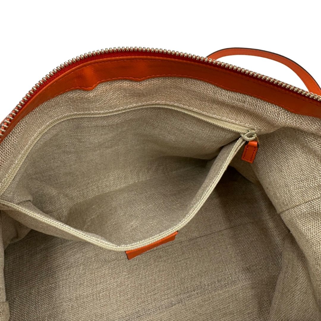 Interno di una borsa Gucci in pelle arancione GG con parti metalliche dorate; munita di doppi manici e una tracolla amovibile e regolabile.