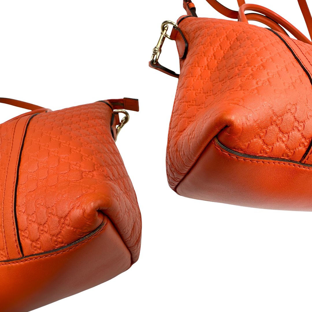 Angoli di una borsa Gucci in pelle arancione GG con parti metalliche dorate; munita di doppi manici e una tracolla amovibile e regolabile.