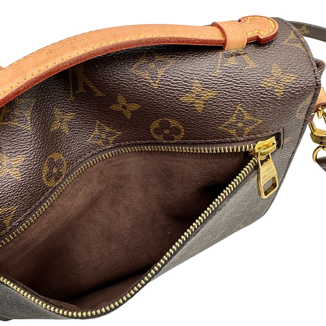 Interno di una borsa Louis Vuitton Métis in canvas marrone monogram con dettagli in vacchetta naturale e parti metalliche dorate. Munita di un manico singolo e una tracolla regolabile e amovibile. Dotata di scatola.
