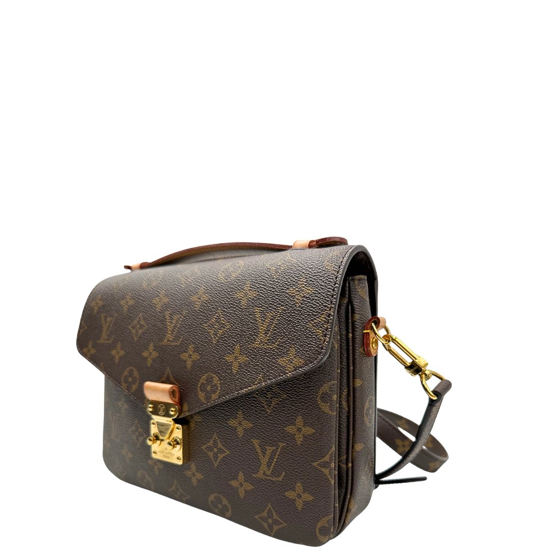 Laterale destro di una borsa Louis Vuitton Métis in canvas marrone monogram con dettagli in vacchetta naturale e parti metalliche dorate. Munita di un manico singolo e una tracolla regolabile e amovibile. Dotata di scatola.