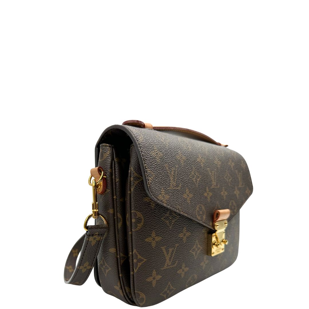 Laterale sinistro di una borsa Louis Vuitton Métis in canvas marrone monogram con dettagli in vacchetta naturale e parti metalliche dorate. Munita di un manico singolo e una tracolla regolabile e amovibile. Dotata di scatola.