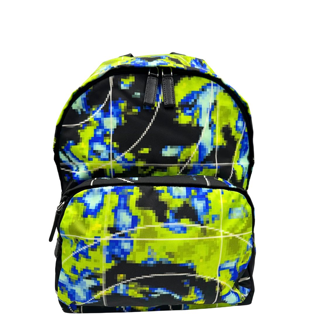 Front di uno zaino Prada Radar in nylon tecnico con chiusura a zip. Design caratterizzato da stampa grafica multicolor effetto radar. Struttura con ampio scomparto principale, tasca frontale a zip e tasca interna con zip. Spallacci regolabili con imbottitura e pannello posteriore traspirante in mesh per un maggiore comfort. Manico superiore in pelle nera saffiano. Dettagli con logo triangolo Prada smaltato applicato sul fronte.