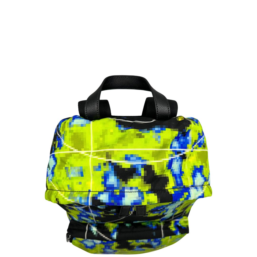 Vista superiore di uno zaino Prada Radar in nylon tecnico con chiusura a zip. Design caratterizzato da stampa grafica multicolor effetto radar. Struttura con ampio scomparto principale, tasca frontale a zip e tasca interna con zip. Spallacci regolabili con imbottitura e pannello posteriore traspirante in mesh per un maggiore comfort. Manico superiore in pelle nera saffiano. Dettagli con logo triangolo Prada smaltato applicato sul fronte.