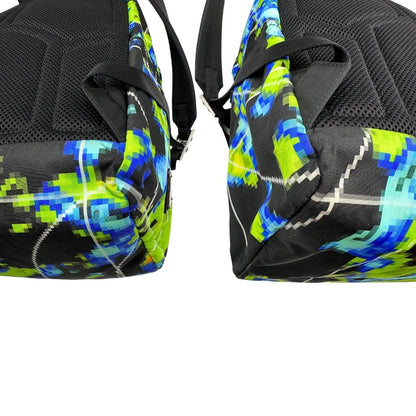 Angoli di uno zaino Prada Radar in nylon tecnico con chiusura a zip. Design caratterizzato da stampa grafica multicolor effetto radar. Struttura con ampio scomparto principale, tasca frontale a zip e tasca interna con zip. Spallacci regolabili con imbottitura e pannello posteriore traspirante in mesh per un maggiore comfort. Manico superiore in pelle nera saffiano. Dettagli con logo triangolo Prada smaltato applicato sul fronte.