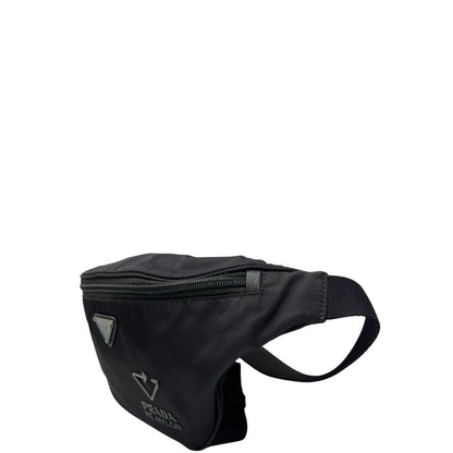 Laterale destro di un marsupio Prada in Re-Nylon nero con dettagli in pelle tono su tono, logo gommato sul front e parti in metallo argentato. Leggermente regolabile, indossabile a marsupio o cross body.