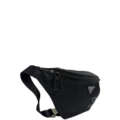 Laterale sinistro di un marsupio Prada in Re-Nylon nero con dettagli in pelle tono su tono, logo gommato sul front e parti in metallo argentato. Leggermente regolabile, indossabile a marsupio o cross body.