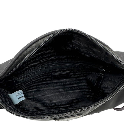 Interno di un marsupio Prada in Re-Nylon nero con dettagli in pelle tono su tono, logo gommato sul front e parti in metallo argentato. Leggermente regolabile, indossabile a marsupio o cross body.