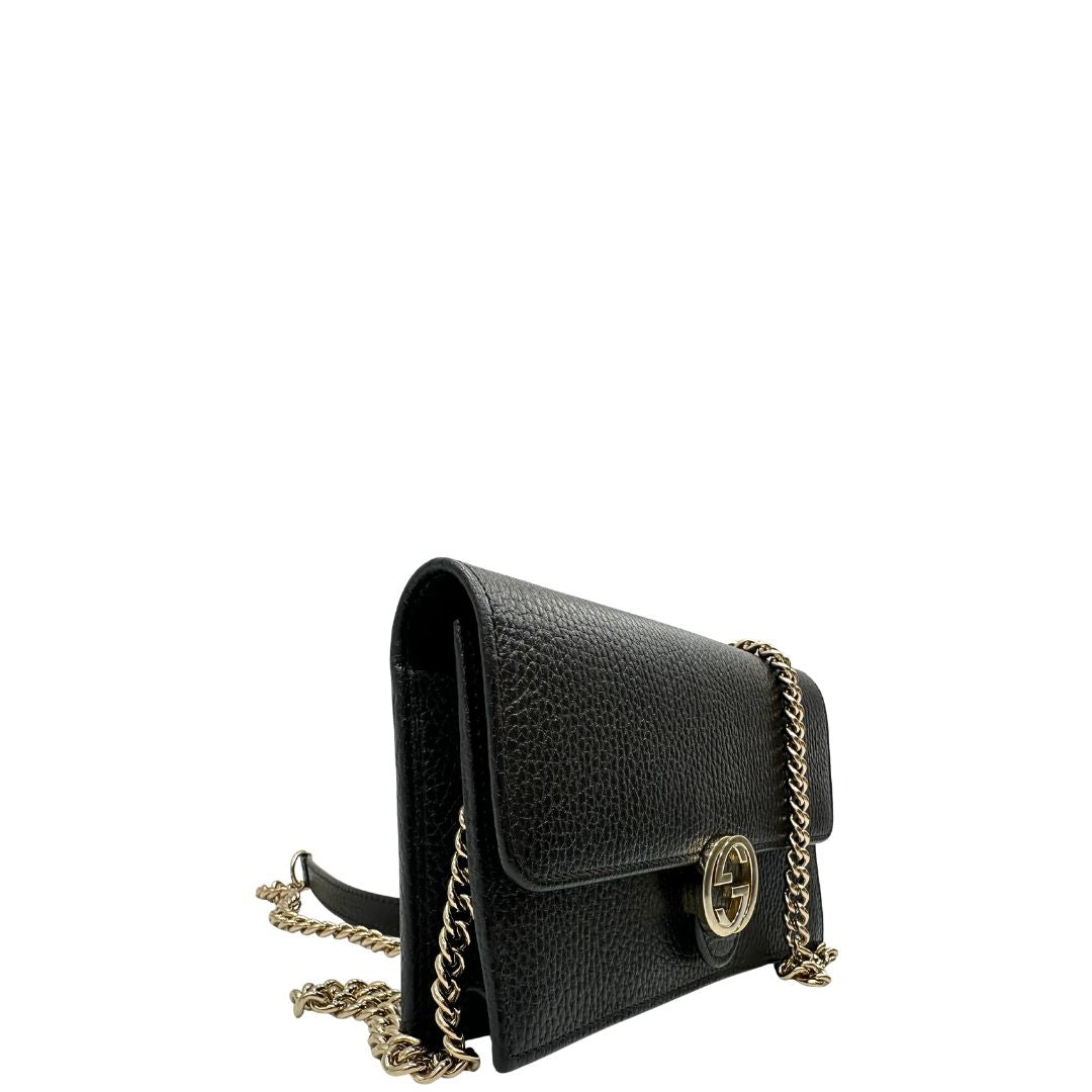 Laterale sinistro di una borsa Gucci Interlocking in pelle martellata nera con parti metalliche oro chiaro. Munita di una tracolla amovibile in catena e spallaccio in pelle. Chiusura con doppie G incrociate. Completa di scatola e dustbag. Indossabile a tracolla.