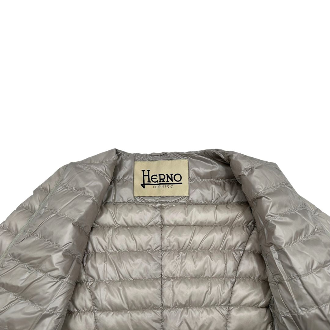 Piumino Herno in 100% poliammide color champagne. Maniche a 3/4 e parti metalliche dorate.