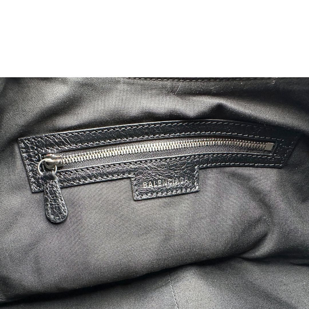 Interno di una borsa Balenciaga Le Cagole Graffiti in pelle nera con stampa graffiti color menta ghiacciata; dotata di manico leggermente regolabile con spallaccio. Pati metalliche argento anticato. Presenta tasca frontale con zip, lacci pendenti e ciondolo a cuore con specchietto integrato. Munita di scatola e dustbag. Indossabile a spalla.
