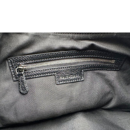 Interno di una borsa Balenciaga Le Cagole Graffiti in pelle nera con stampa graffiti color menta ghiacciata; dotata di manico leggermente regolabile con spallaccio. Pati metalliche argento anticato. Presenta tasca frontale con zip, lacci pendenti e ciondolo a cuore con specchietto integrato. Munita di scatola e dustbag. Indossabile a spalla.