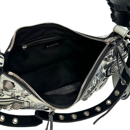 Interno di una borsa Balenciaga Le Cagole Graffiti in pelle nera con stampa graffiti color menta ghiacciata; dotata di manico leggermente regolabile con spallaccio. Pati metalliche argento anticato. Presenta tasca frontale con zip, lacci pendenti e ciondolo a cuore con specchietto integrato. Munita di scatola e dustbag. Indossabile a spalla.