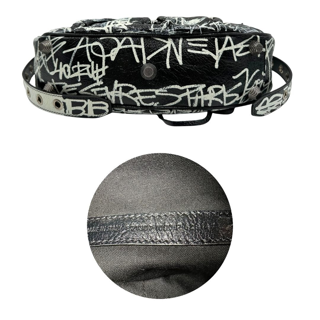 Base e codice di una borsa Balenciaga Le Cagole Graffiti in pelle nera con stampa graffiti color menta ghiacciata; dotata di manico leggermente regolabile con spallaccio. Pati metalliche argento anticato. Presenta tasca frontale con zip, lacci pendenti e ciondolo a cuore con specchietto integrato. Munita di scatola e dustbag. Indossabile a spalla.