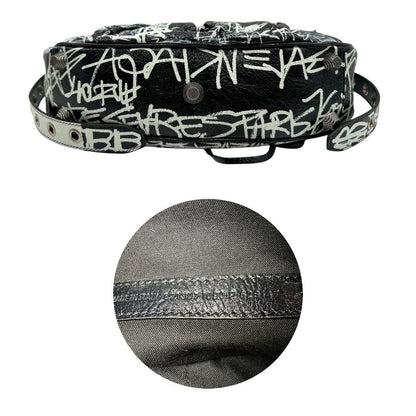 Base e codice di una borsa Balenciaga Le Cagole Graffiti in pelle nera con stampa graffiti color menta ghiacciata; dotata di manico leggermente regolabile con spallaccio. Pati metalliche argento anticato. Presenta tasca frontale con zip, lacci pendenti e ciondolo a cuore con specchietto integrato. Munita di scatola e dustbag. Indossabile a spalla.