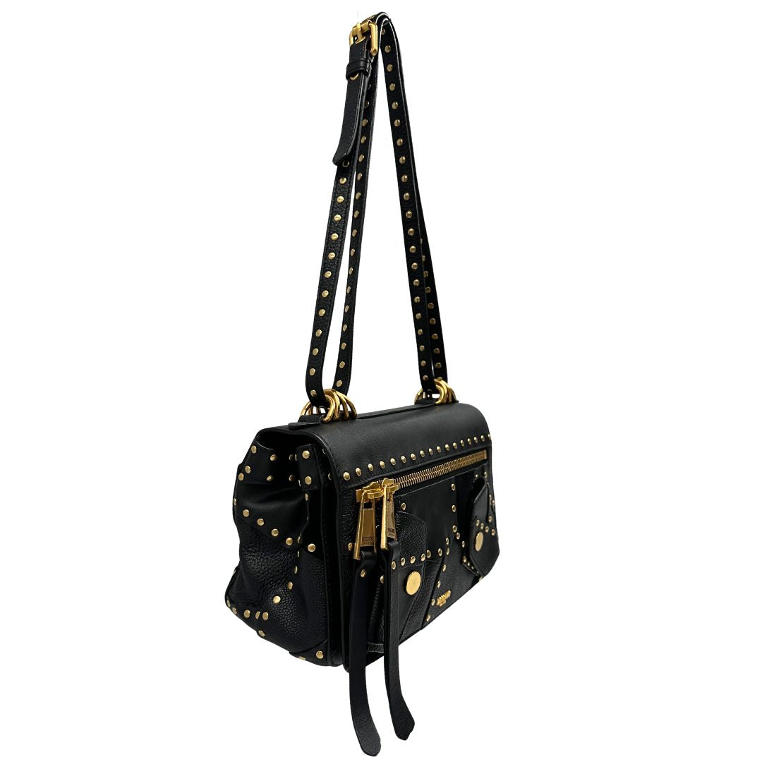 Lato destro di una Borsa Moschino in pelle nera con inserti metallici dorati, arricchita da borchie dorate, zip frontale con maxi tirazip e applicazioni geometriche. munita di una tracolla regolabile non amovibile. Completa di Card d'autenticità Misure. Originale, Usata, di lusso, in ottime condizioni.