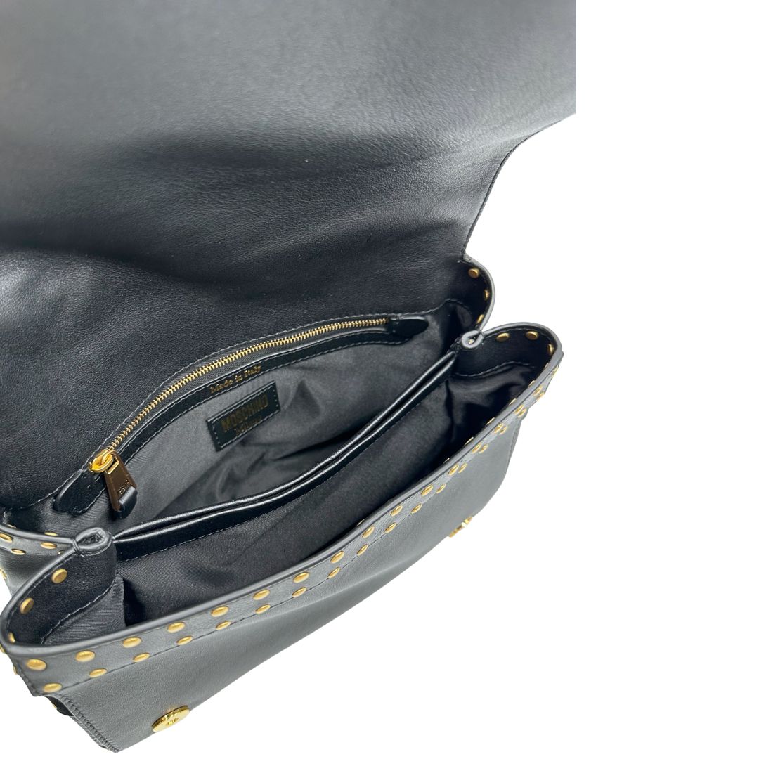 Interno di una Borsa Moschino in pelle nera con inserti metallici dorati, arricchita da borchie dorate, zip frontale con maxi tirazip e applicazioni geometriche. munita di una tracolla regolabile non amovibile. Completa di Card d'autenticità Misure. Originale, Usata, di lusso, in ottime condizioni.