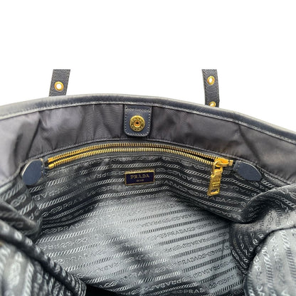 Interno di una borsa Prada in nylon blu navy e finiture in pelle saffiano tono su tono, con parti metalliche dorate; munita di un accessorio porta address e doppi manici leggermente regolabili. Indossabile a spalla. Completa di dustbag e card d'autenticità.