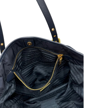 Interno di una borsa Prada in nylon blu navy e finiture in pelle saffiano tono su tono, con parti metalliche dorate; munita di un accessorio porta address e doppi manici leggermente regolabili. Indossabile a spalla. Completa di dustbag e card d'autenticità.