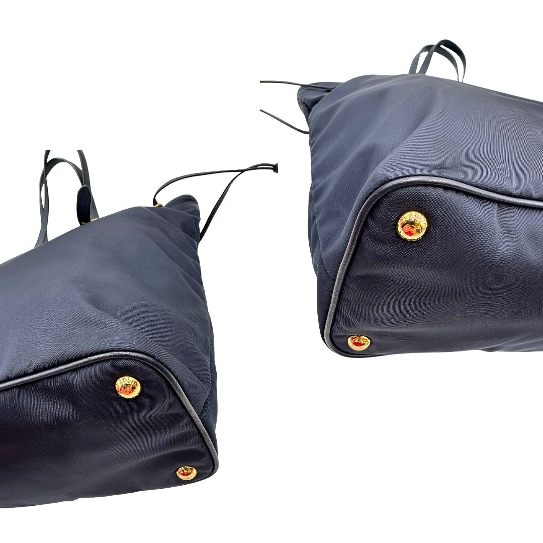 Angoli di una borsa Prada in nylon blu navy e finiture in pelle saffiano tono su tono, con parti metalliche dorate; munita di un accessorio porta address e doppi manici leggermente regolabili. Indossabile a spalla. Completa di dustbag e card d'autenticità.