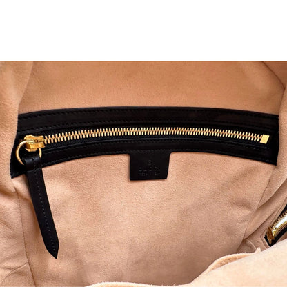 Interno di un Zaino Gucci in canvas GG beige con finiture in pelle nere e parti metalliche dorate; presenta una stampa di api dorate su tutta la superficie, munito di un manico e bretelle in tessuto regolabili. Originale, usato, di lusso, in ottime condizioni.