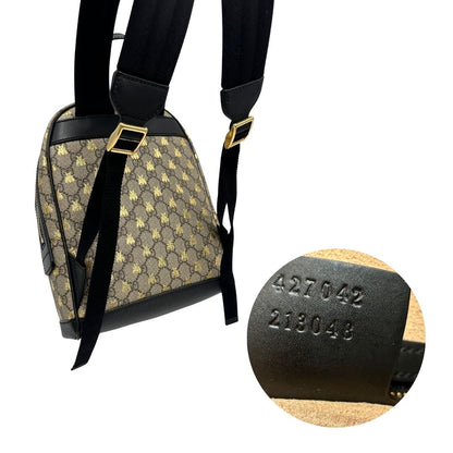 Zaino Gucci in canvas GG beige con finiture in pelle nere e parti metalliche dorate; presenta una stampa di api dorate su tutta la superficie, munito di un manico e bretelle in tessuto regolabili. Originale, usato, di lusso, in ottime condizioni.