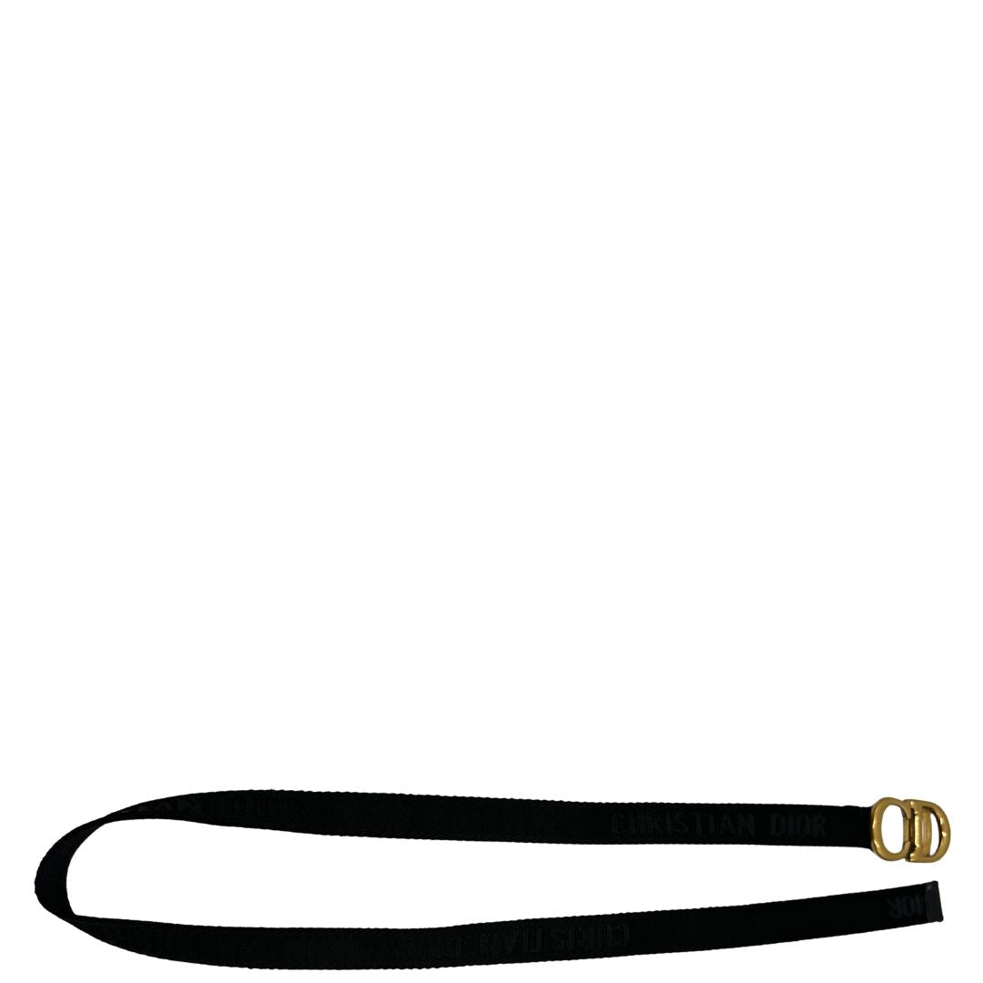 Cintura Christian Dior in tessuto logato nera, impreziosita da fibbia con CD in metallo dorato. Completa di dustbag. Chiusura a cricchetto.