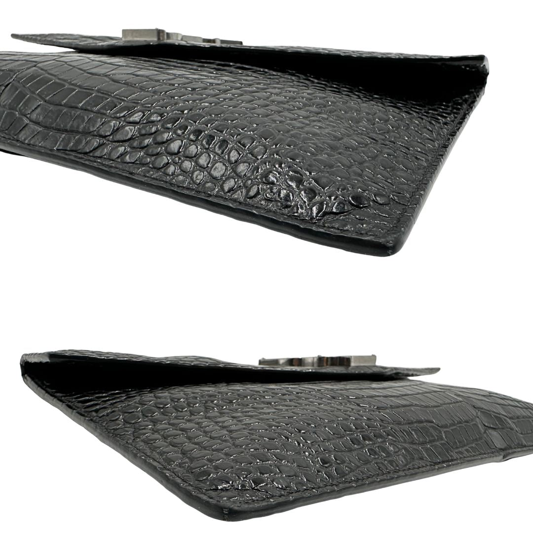 Angoli di una pochette Saint Laurent in pelle nera lucida effetto cocco, impreziosita dal logo Cassandre sul front in metallo argentato. Munita di dustbag.