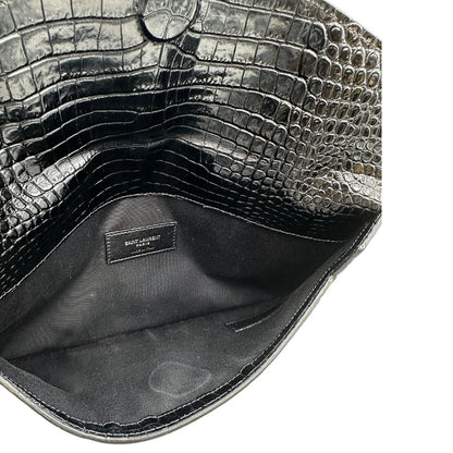 Interno di una pochette Saint Laurent in pelle nera lucida effetto cocco, impreziosita dal logo Cassandre sul front in metallo argentato. Munita di dustbag.