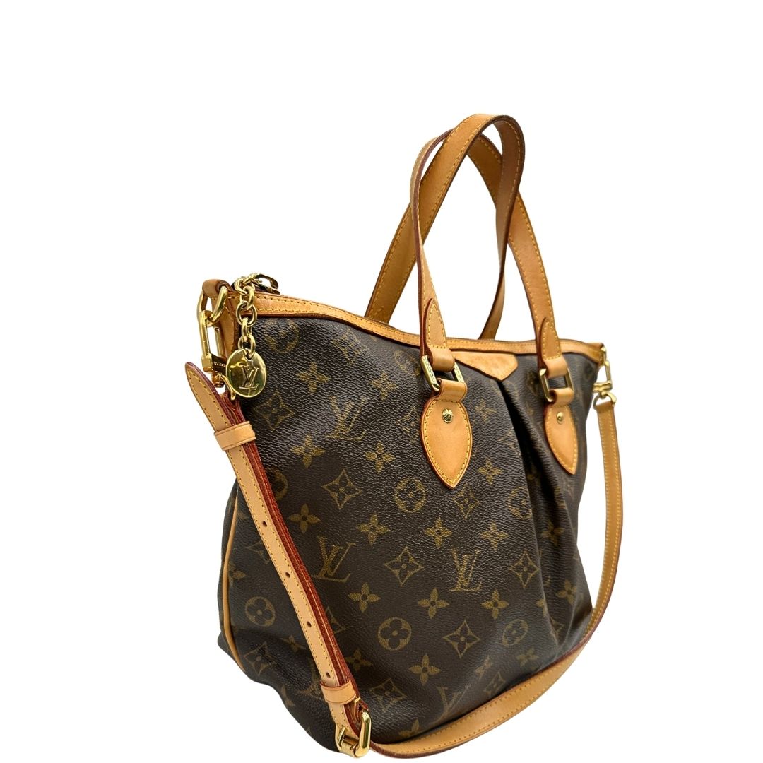 Laterale sinistro di una borsa Louis Vuitton in canvas marrone monogram con parti metalliche dorate e finiture in vacchetta naturale; munita di una tracolla amovibile e regolabile e doppi manici. Indossabile a spalla oppure a mano.