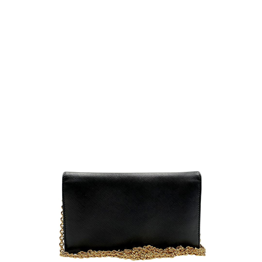 Retro di un WOC Salvatore Ferragamo in pelle saffiano nera con parti metalliche oro. Munita di una tracolla in catena amovibile e non regolabile. Chiusura con fiocco. Completo di dustbag. Indossabile a tracolla.