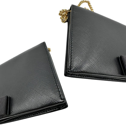 Angoli di un WOC Salvatore Ferragamo in pelle saffiano nera con parti metalliche oro. Munita di una tracolla in catena amovibile e non regolabile. Chiusura con fiocco. Completo di dustbag. Indossabile a tracolla.