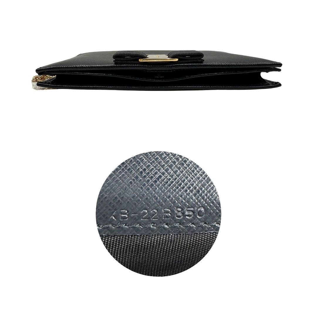 Base e codice di un WOC Salvatore Ferragamo in pelle saffiano nera con parti metalliche oro. Munita di una tracolla in catena amovibile e non regolabile. Chiusura con fiocco. Completo di dustbag. Indossabile a tracolla.