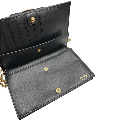 Apertura di un WOC Salvatore Ferragamo in pelle saffiano nera con parti metalliche oro. Munita di una tracolla in catena amovibile e non regolabile. Chiusura con fiocco. Completo di dustbag. Indossabile a tracolla.